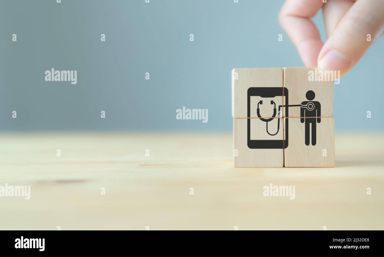Assistenza sanitaria digitale e tecnologia medica futuristica. Mano che tiene cubi di legno con simboli di M-Health, mobile healthcare, online medico, Foto Stock