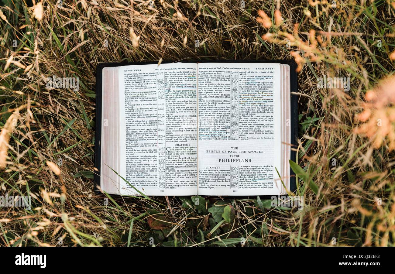 La Sacra Bibbia cristiana si apre in un campo caldo e soleggiato al libro dei Filippesi, una lettera di Paolo in te nuovo Testamento Foto Stock