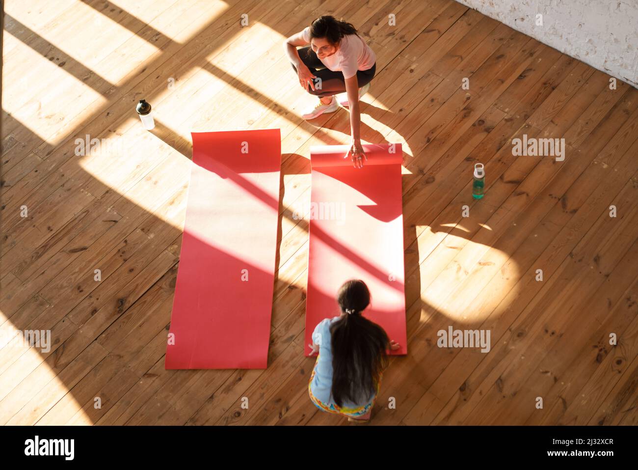 Giovane bianco due donne che srotolano materassini fitness in interni Foto Stock
