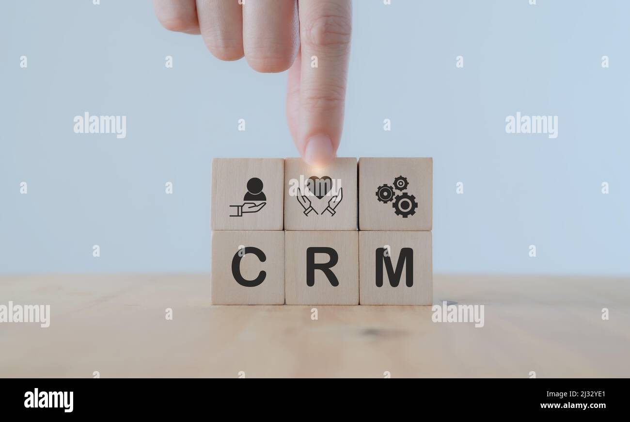 Concetto di Customer Relationship Management (CRM). Strategia di marketing per la fidelizzazione e il sostegno dei clienti. Mano mette il cubo di legno con l'icona di 'relazionship' Foto Stock