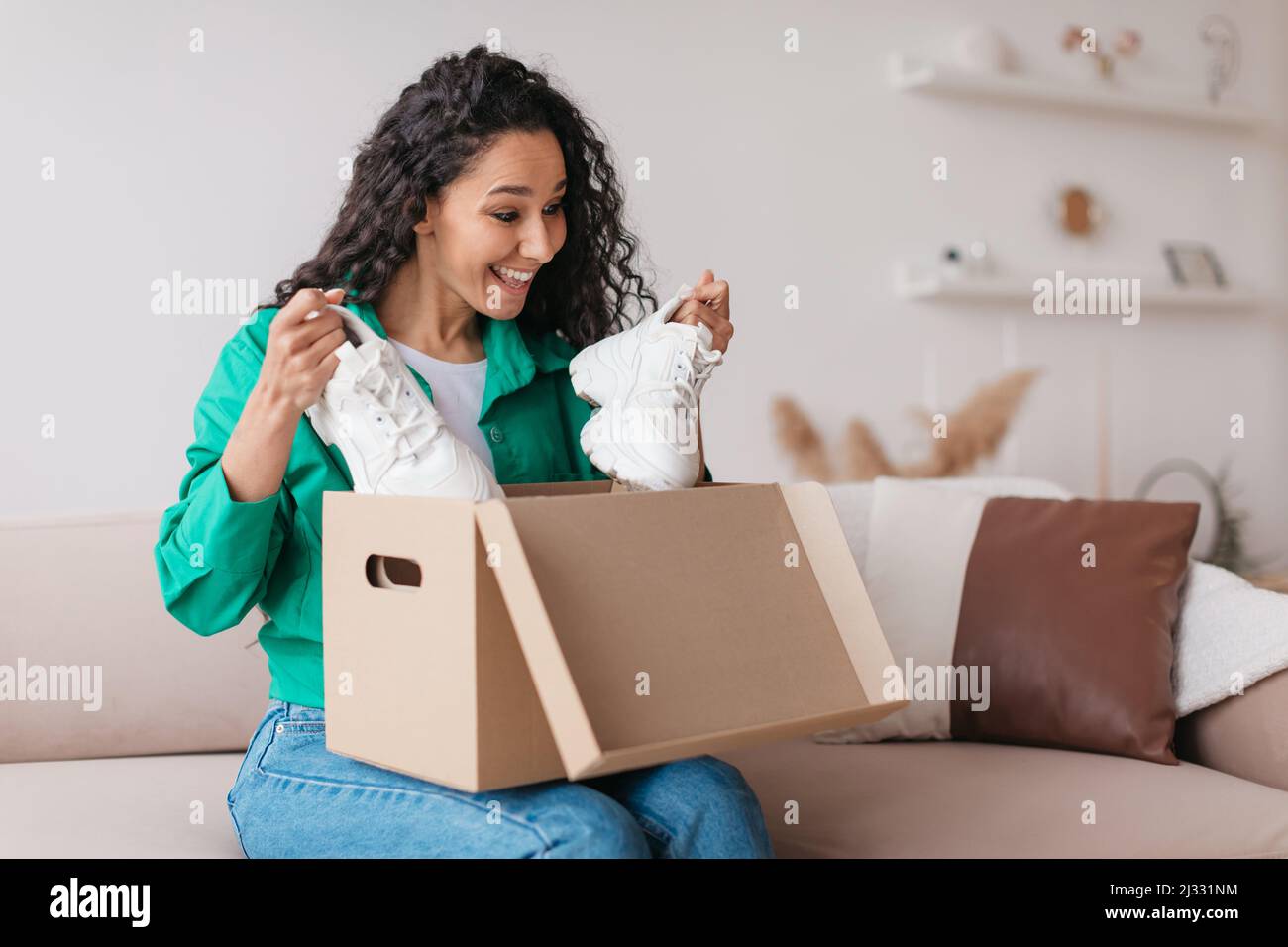 Cheerful cliente Lady Holding scarpe di disimballaggio scatola a casa Foto Stock