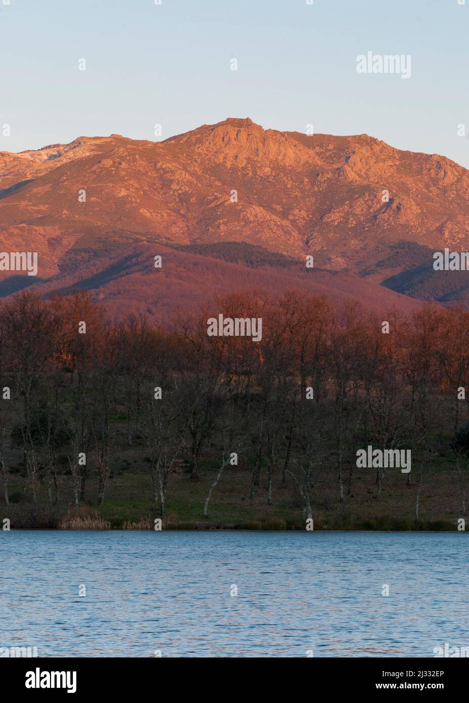Montagna con luce arancione al tramonto sul lago d'acqua in autunno in verticale Foto Stock Montagna con luce arancione al tramonto sul lago d'acqua in autunno in verticale Foto Stock