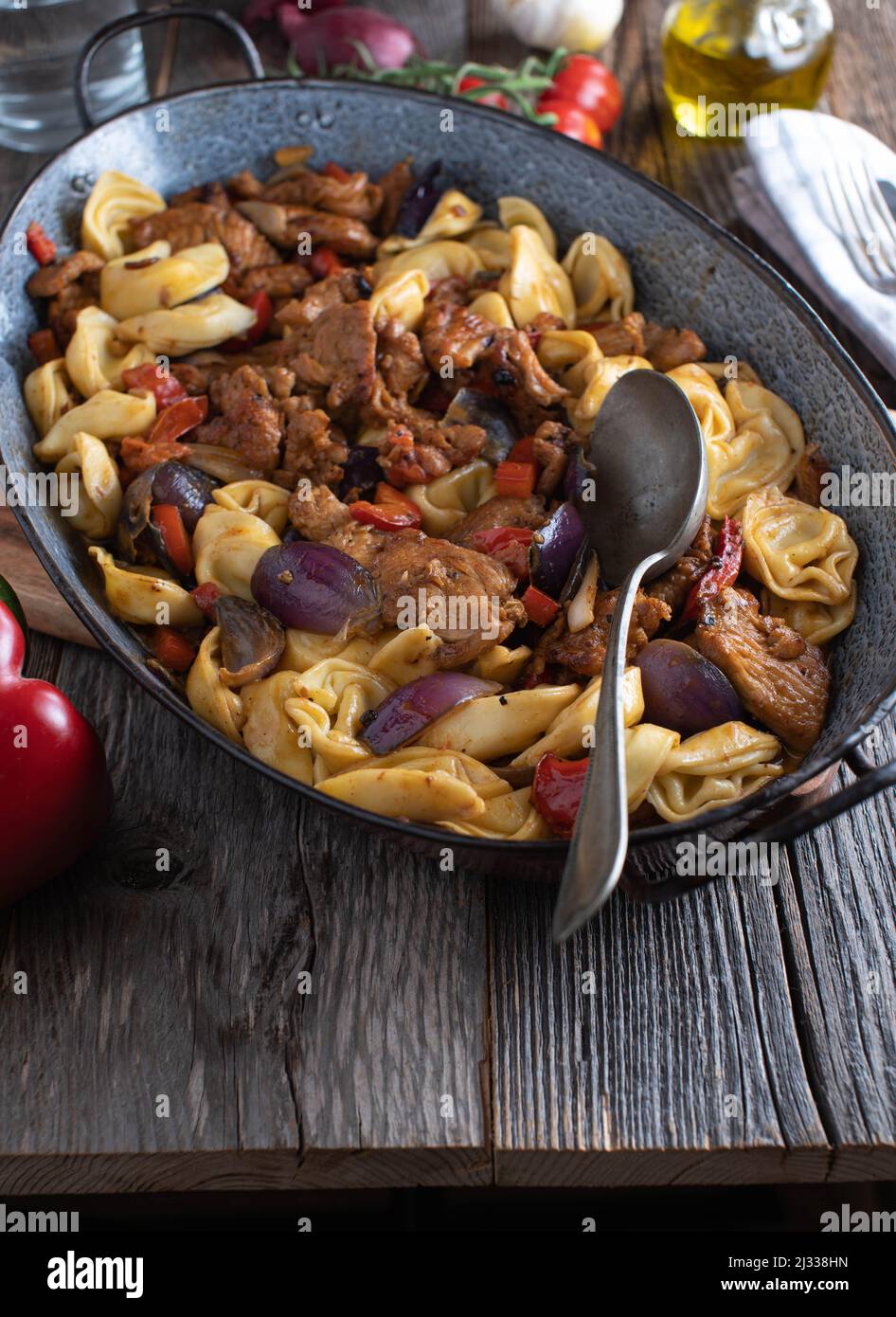 Tortellini con carne saltata, verdure e salsa in una teglia rustica. Cucina italiana Foto Stock