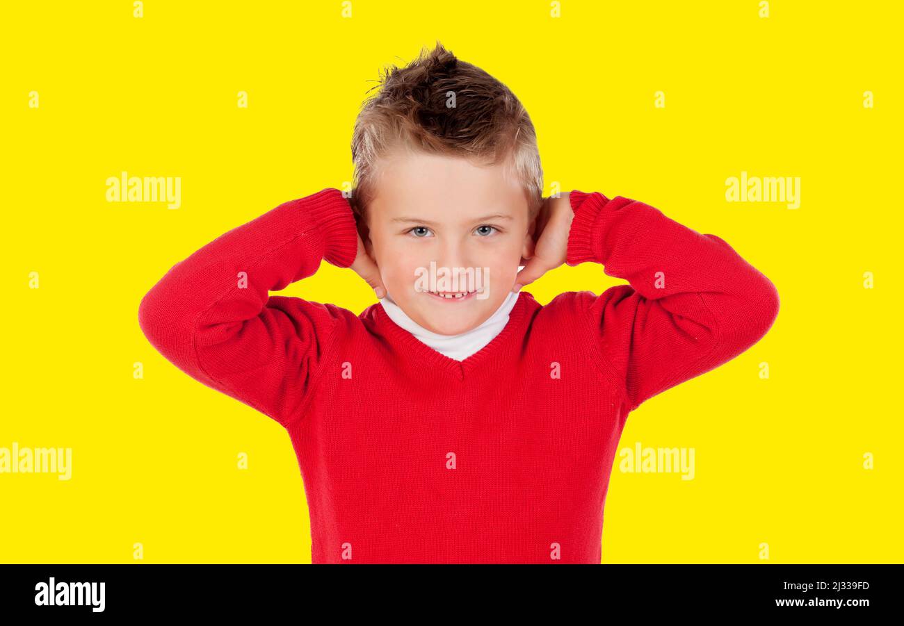 Il bambino infastidito di un forte rumore isolato su uno sfondo giallo Foto Stock