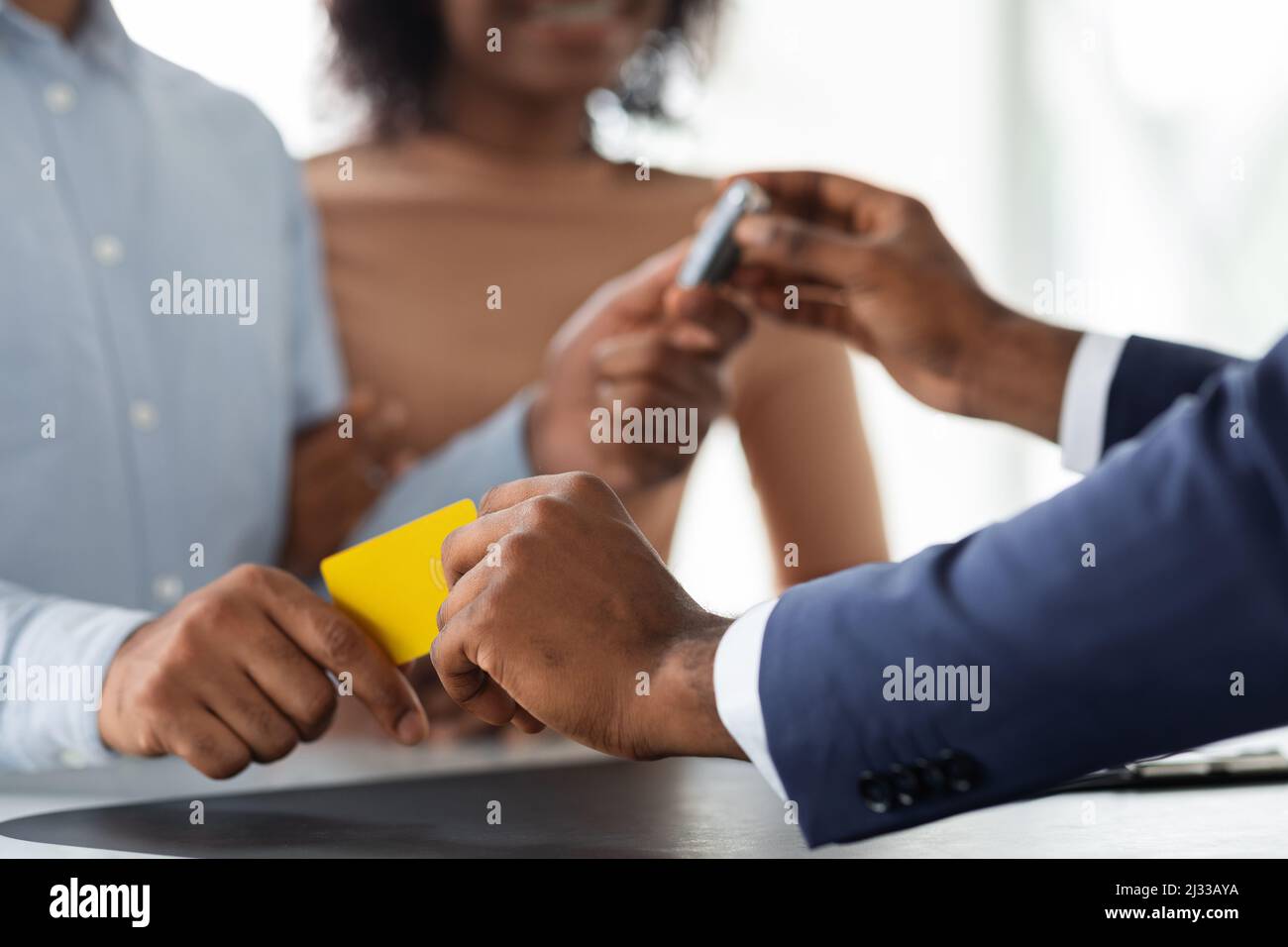 Black Manager prendere la carta di credito e dare le chiavi dell'auto alla giovane coppia Foto Stock