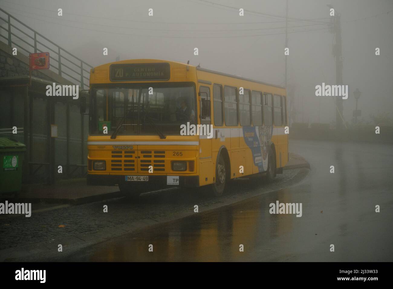 Un autobus giallo alla stazione in attesa di nebbia tempo Foto Stock