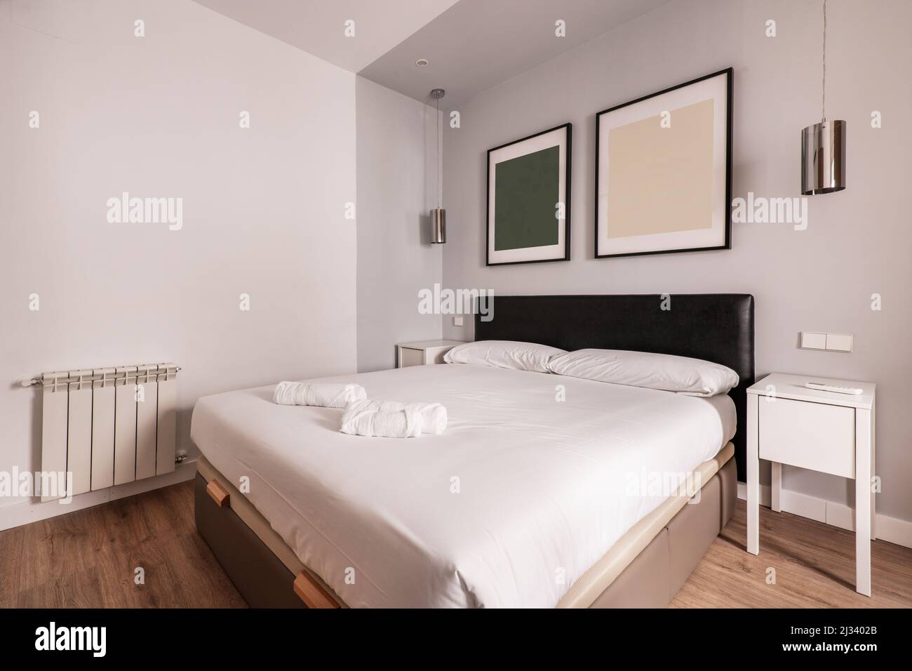 Camera da letto con letto matrimoniale con testiera imbottita in skay nero e comodini bianchi Foto Stock