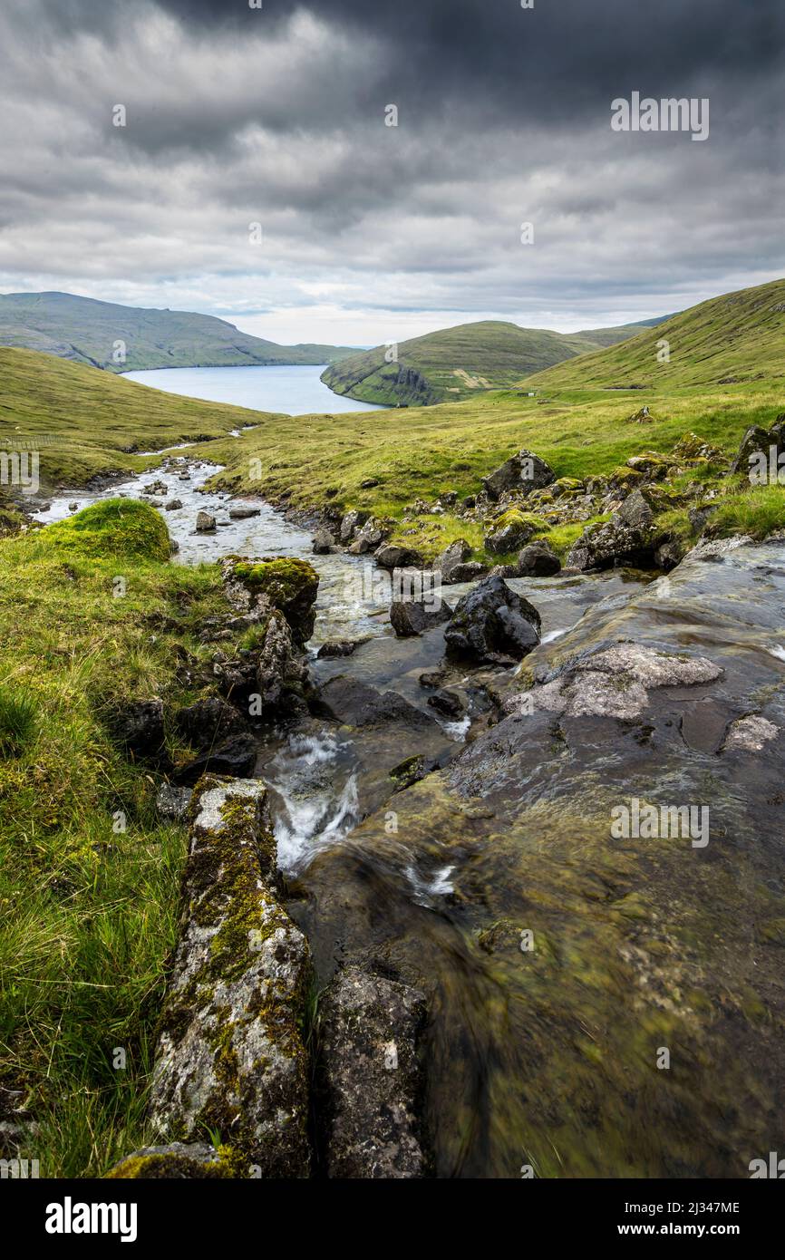 Corso di fiume a Disvoy Fjord, Streymoy, Isole Faeroe. Nuvole scure. Foto Stock