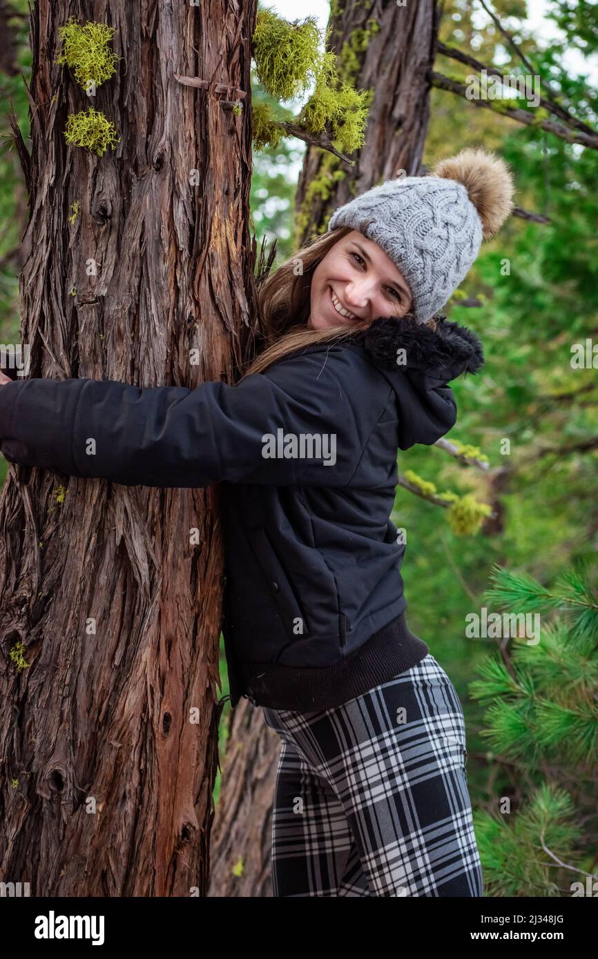 Ritratto di una ragazza sorridente che abbraccia un pino. Foto Stock