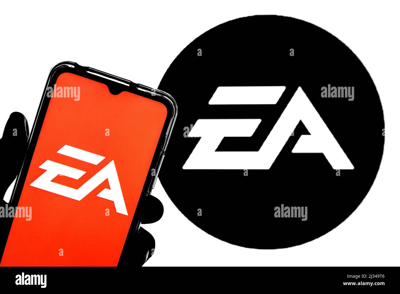 In questa figura è illustrato un logo di Electronic Arts Inc. Visualizzato su uno smartphone con il logo di Electronic Arts Inc. Sullo sfondo. Foto Stock