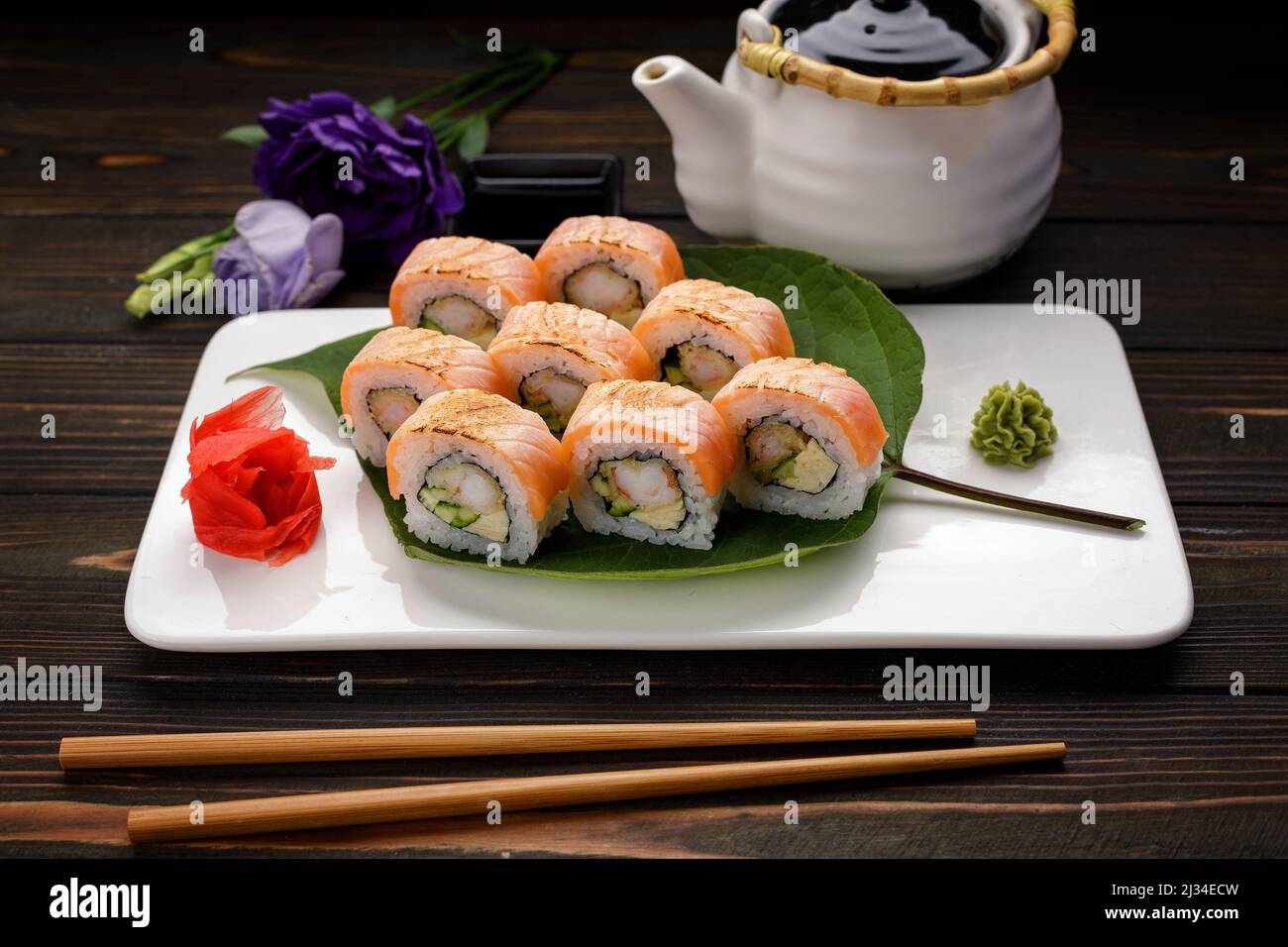 Kimono di sushi Maki con decor. Con salmone, gamberi, cetrioli, su un piatto, su sfondo di legno Foto Stock