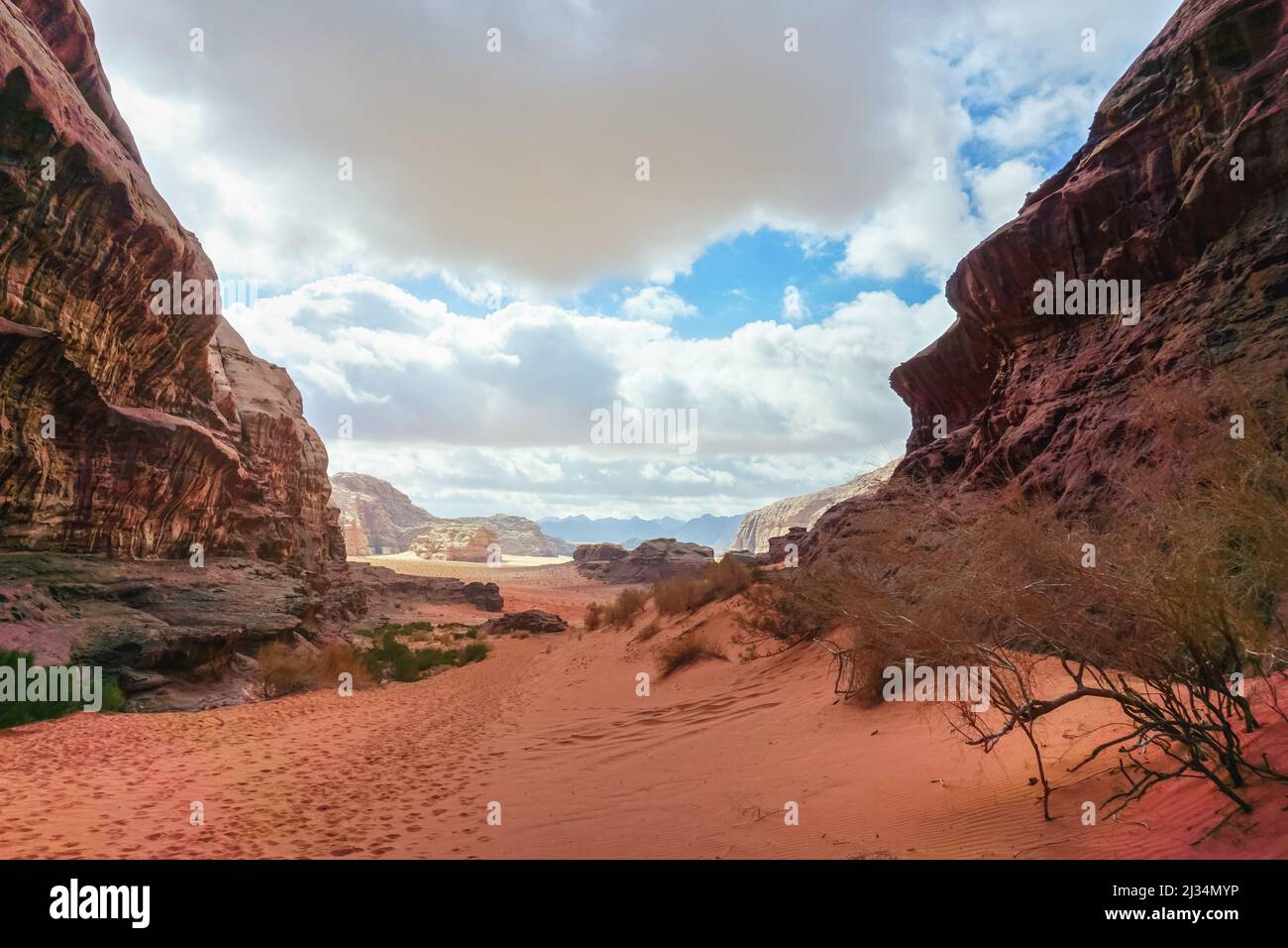 Canyon roccioso con sabbia rossa sulla terra, cielo blu in lontananza - scenario Wadi Rum Foto Stock
