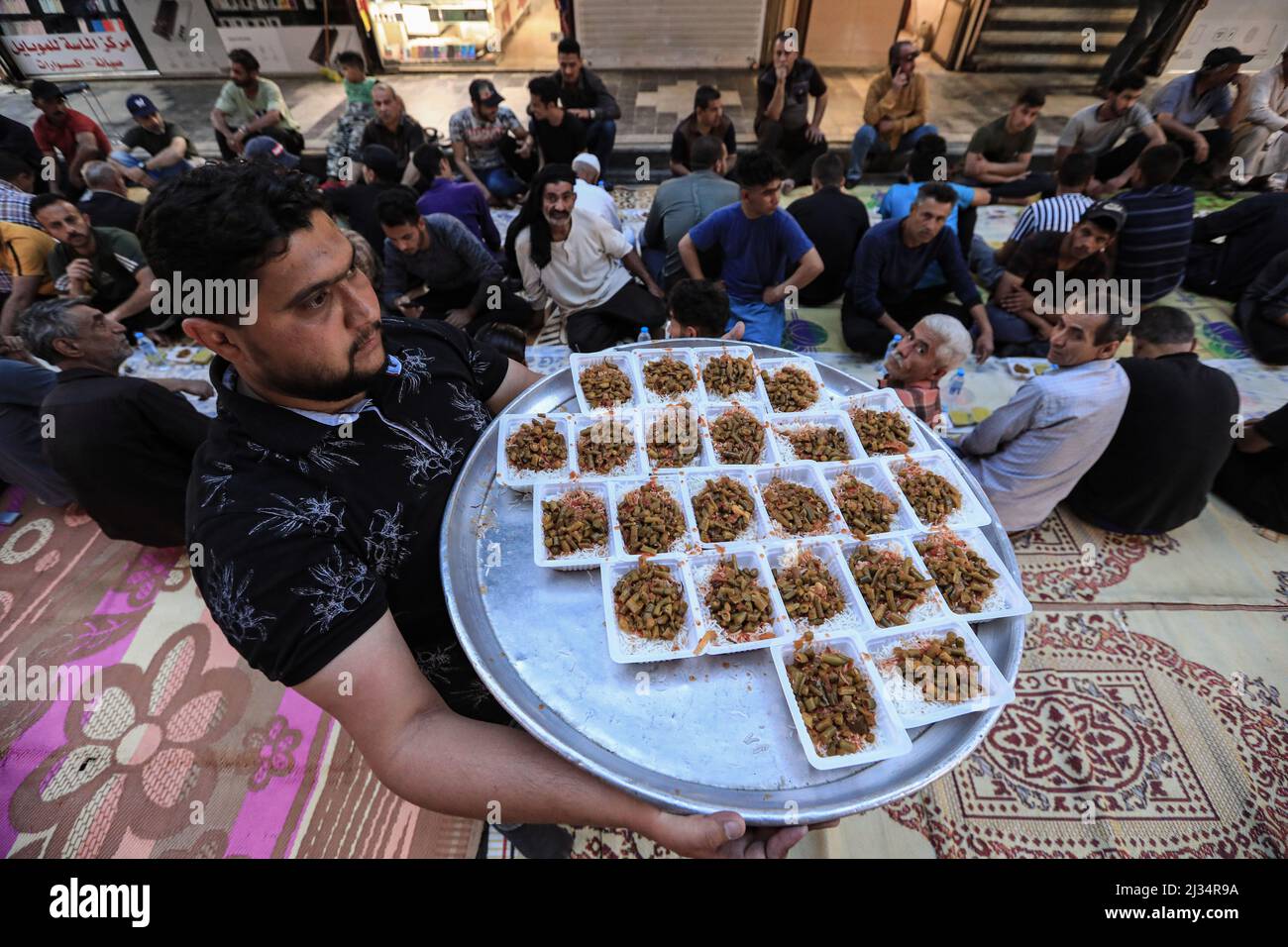 Baghdad, Iraq. 05th Apr 2022. Un volontario serve cibo per il pasto Iftar (breaking fast) nel Kadhimiya durante il mese santo del Ramadan. Credit: Ameer al-Mohammedawi/dpa/Alamy Live News Foto Stock