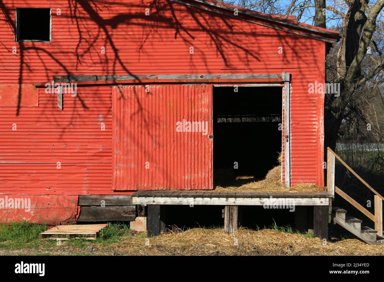 una porta di fienile rosso porte appese metallo ondulato ingresso cavallo mucca bestiame bestiame riparo alimentazione magazzino di allevamento edificio Foto Stock