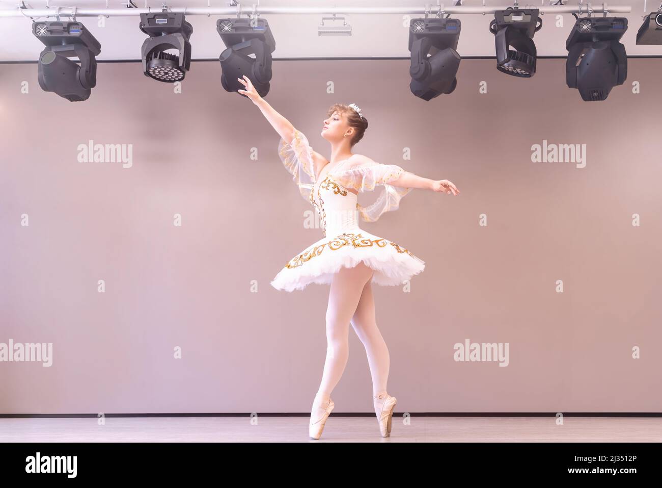 Giovane ballerina classica in studio è in piedi su tiptoe.Young bella ballerina caucasica pratica posizioni balletto in tutu gonna di Foto Stock