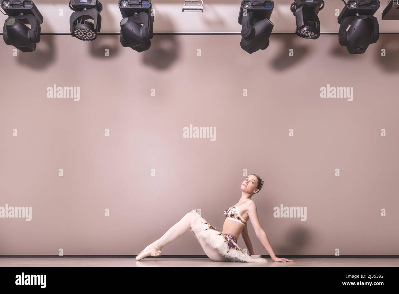 giovane bella bella ballerina caucasica pratica posizioni balletto in gonna tutu. Ballerina classica seduta sul pavimento nello studio Foto Stock