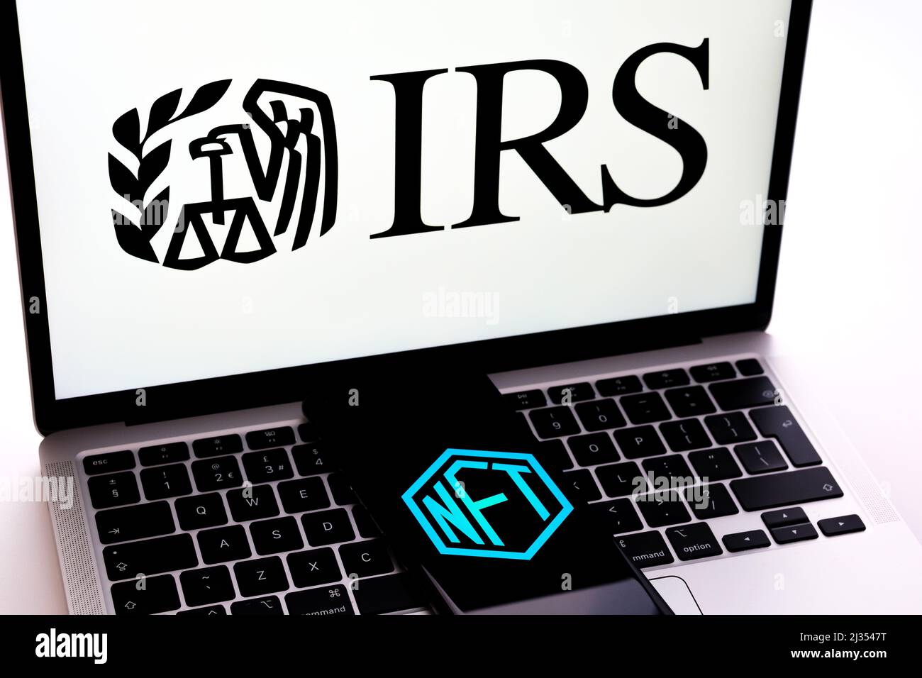 Logo NFT visualizzato sullo smartphone posizionato sulla tastiera del laptop con logo IRS. Messa a fuoco selettiva. Concetto. Stafford, Regno Unito, 5 aprile 2022 Foto Stock
