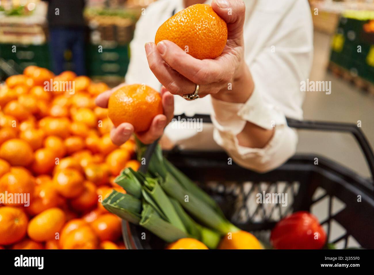 Il cliente tiene i tangerini nelle mani mentre acquista nel reparto frutta nel supermercato Foto Stock