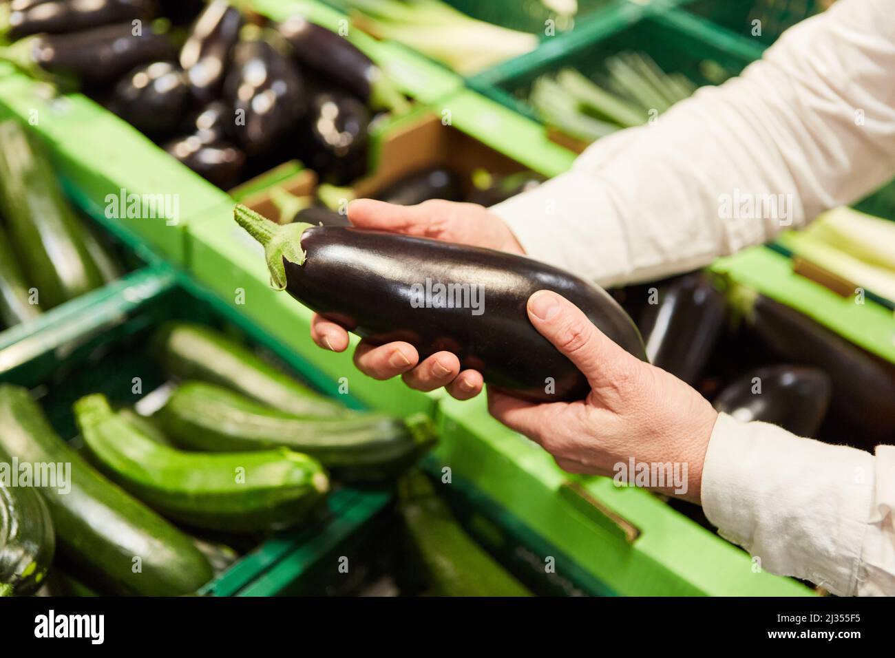 Il cliente quando acquista al mercato settimanale o nel discount tiene la melanzana nelle sue mani Foto Stock