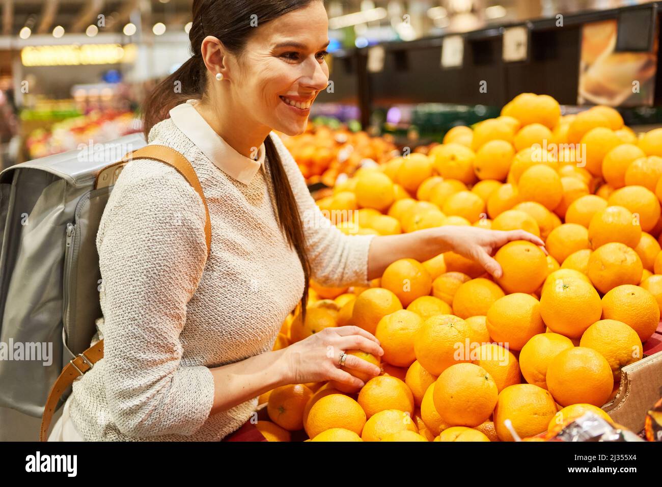 Giovane donna come cliente soddisfatto che acquista le arance allo stand di frutta nel supermercato Foto Stock