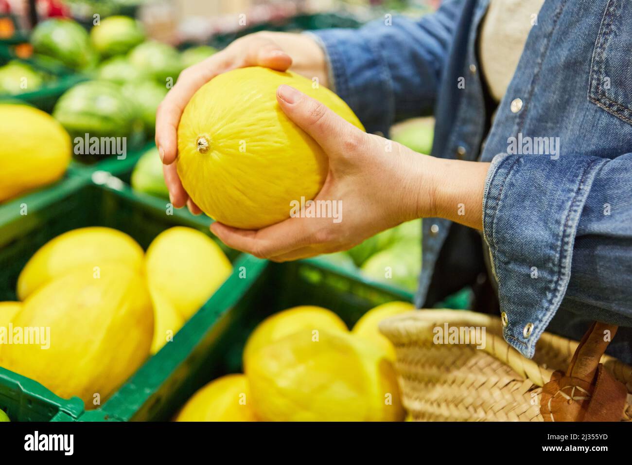 Mani che tengono un melone di nido d'ape mentre si acquista al supermercato come una dieta sana Foto Stock