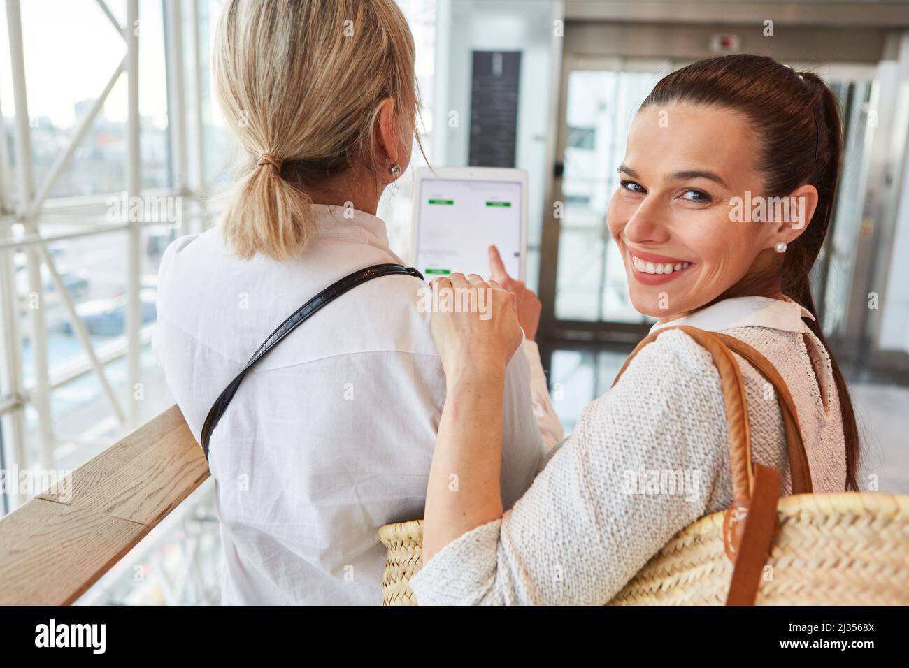 Due amici nel centro commerciale con un tablet PC mentre acquistano online a confronto i prezzi Foto Stock