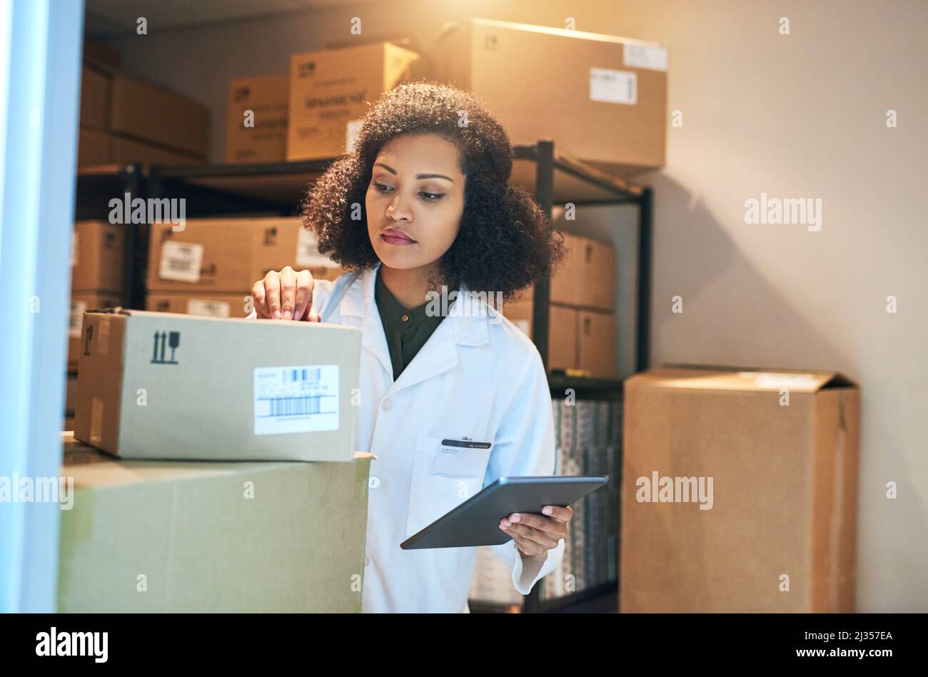 Coordinare il processo di controllo delle scorte con la tecnologia intelligente. Scatto di una giovane donna che usa un tablet digitale mentre fa l'inventario nel magazzino di un Foto Stock