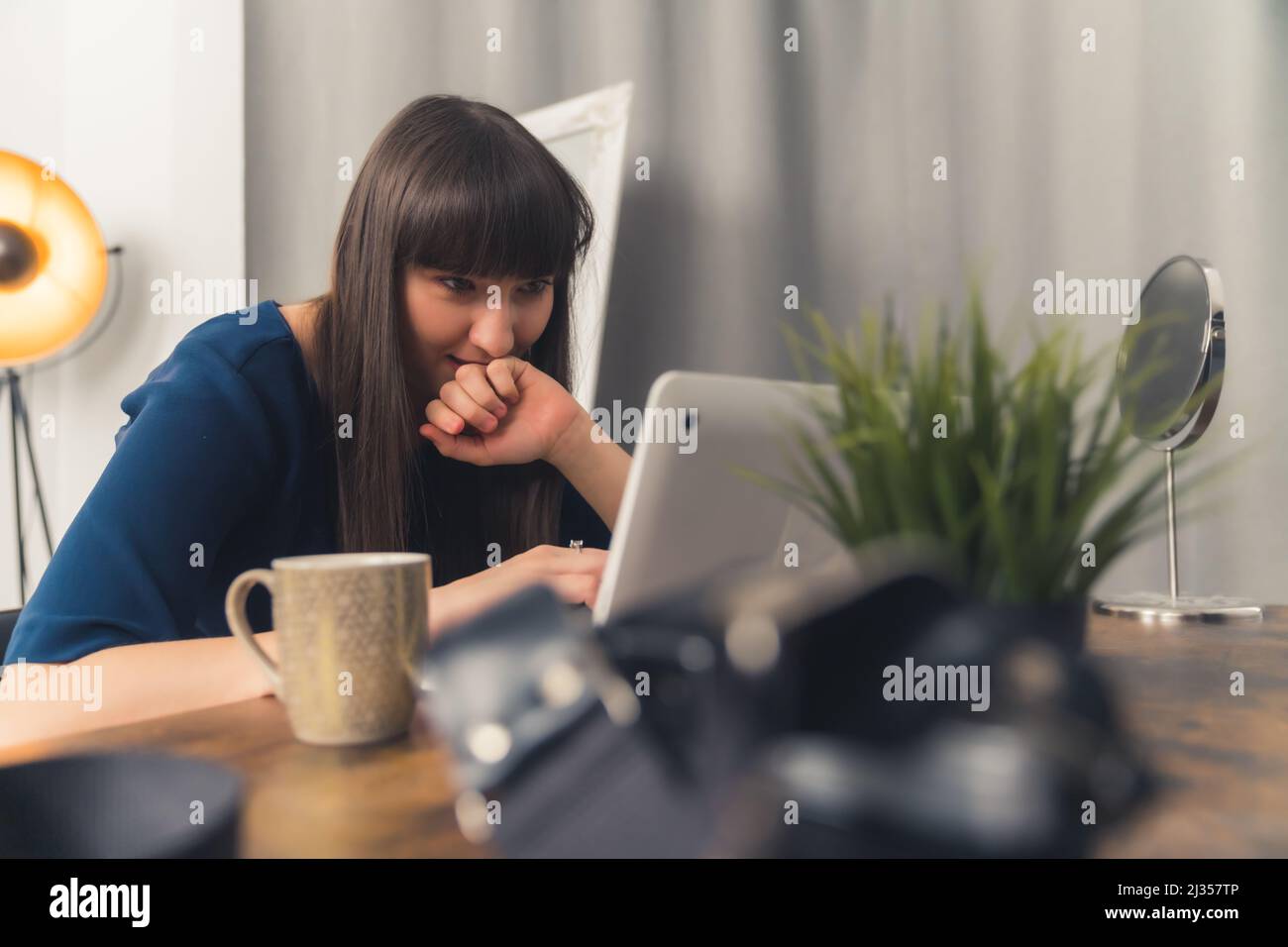 Attraente giovane donna con capelli scuri lavora a casa lavoro remoto concetto grigio sfondo selettivo messa a fuoco spazio copia. Foto di alta qualità Foto Stock