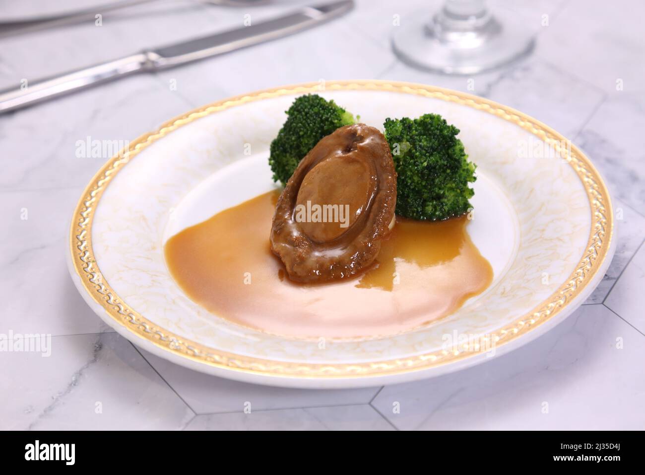 Testa Abalone premium in un piatto isolato su sfondo grigio vista laterale del cibo di Hong kong Foto Stock