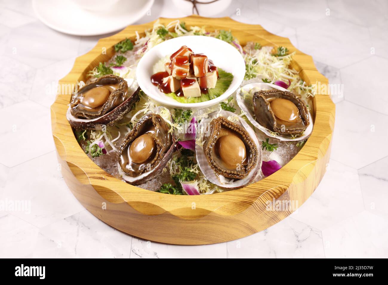Abalone imperiale con foie gras in un piatto isolato su sfondo grigio vista laterale del cibo di Hong kong Foto Stock