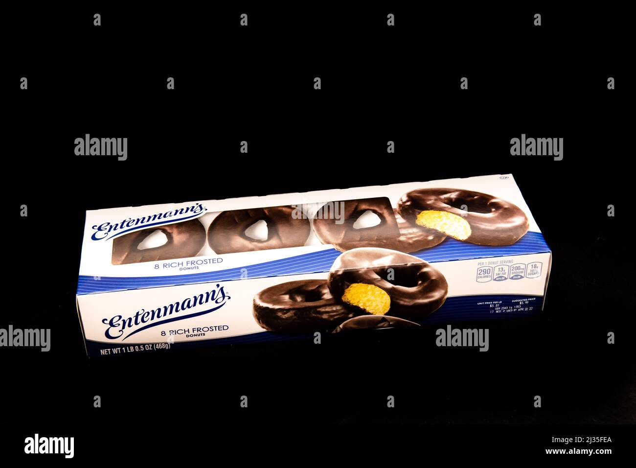 Una scatola di 8 ciambelle glassate ricche di Entenmann, con un rivestimento al cioccolato su un centro dolce giallo morbido isolato sul nero Foto Stock
