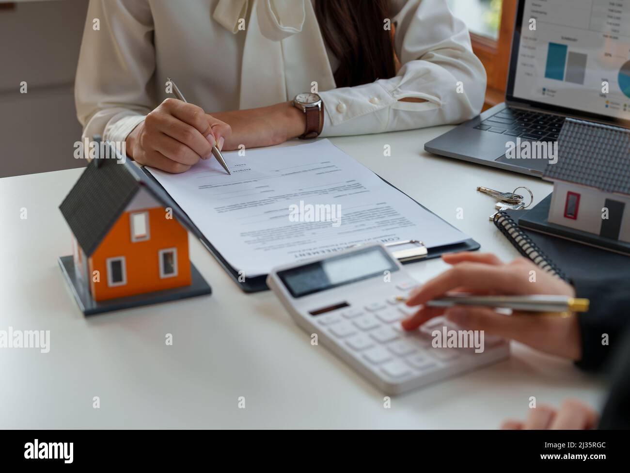 Calcolo dei mediatori immobiliari per la valutazione del prestito e consigliare ai clienti di firmare i loro nomi. Agente immobiliare, intermediario immobiliare, investimento immobiliare Foto Stock
