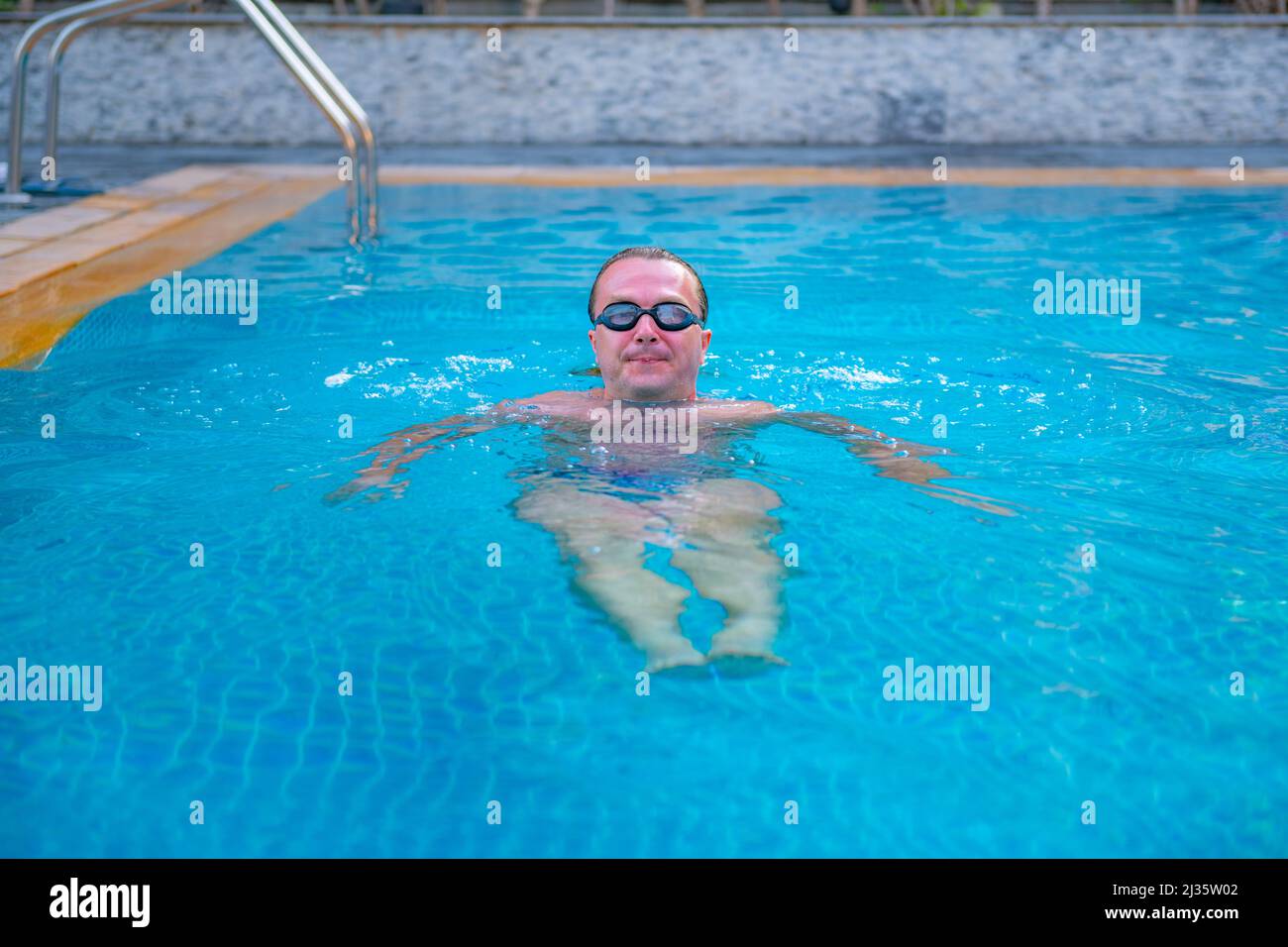 un uomo nuota in una piscina blu Foto Stock