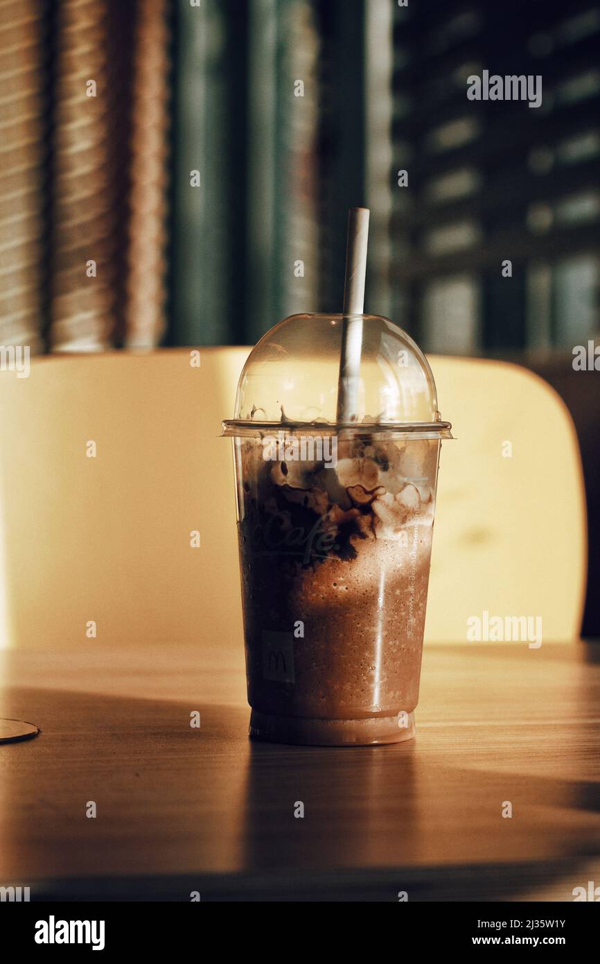 Un primo piano di frullato al cioccolato su un tavolo di legno in una caffetteria con sfondo sfocato Foto Stock