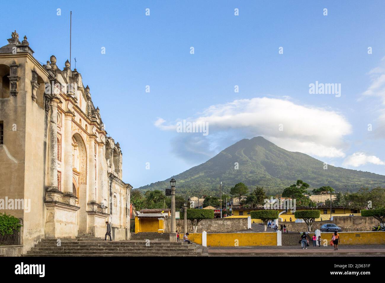 Le persone che vanno a messa nella chiesa di San Juan del Obispo durante il pomeriggio. Sullo sfondo il vulcano Agua con una nuvola in cima può essere apprezzato Foto Stock