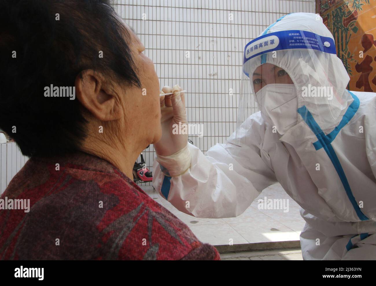 HANDAN, CINA - 5 APRILE 2022 - Un operatore medico prende campioni di acido nucleico per una persona anziana con mobilità limitata nella città di Handan, nella provincia di Hebei Foto Stock