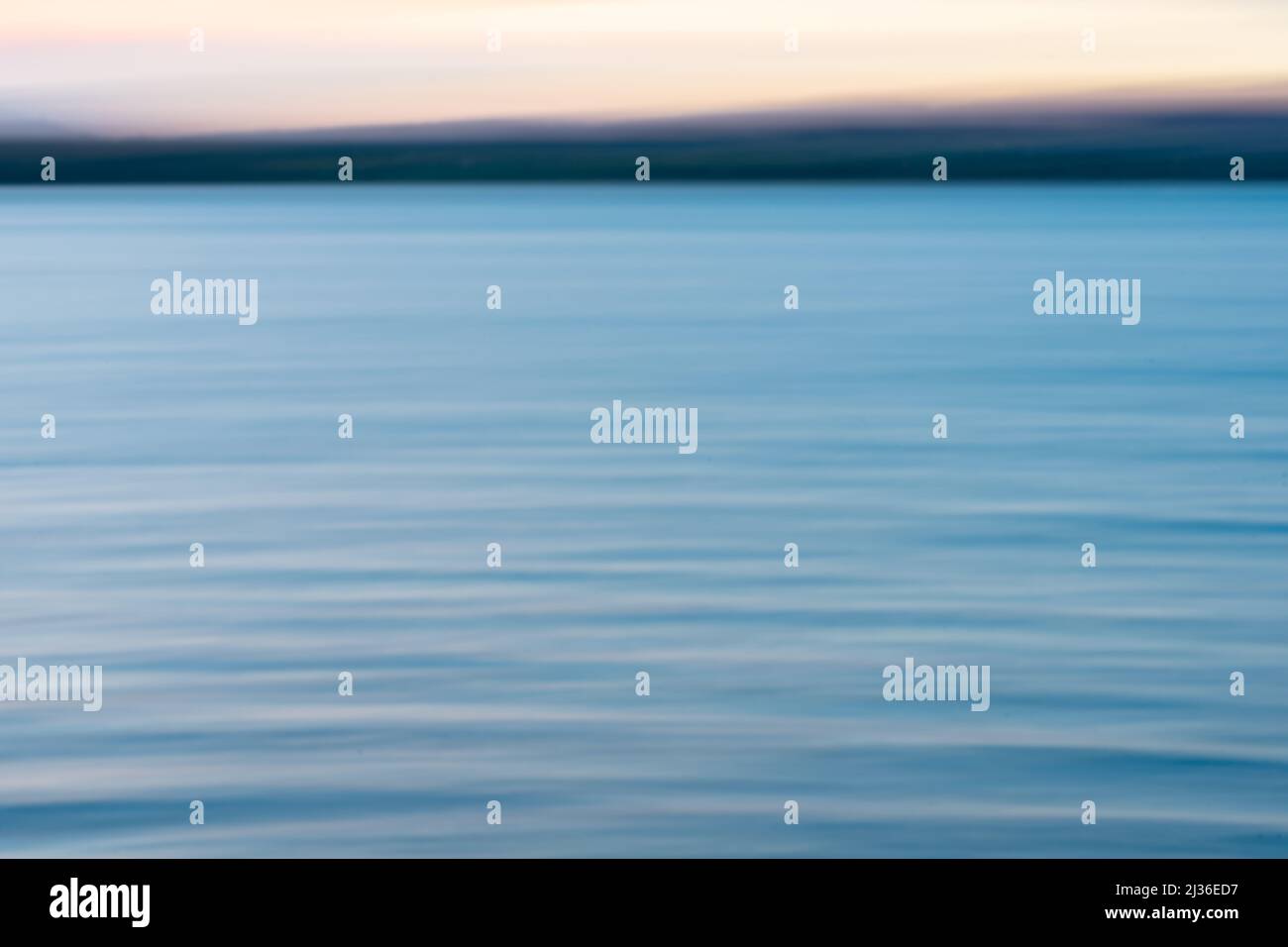 Immagine di sfondo costiero dei colori del tramonto sull'acqua e nel cielo sopra l'orizzonte. Foto Stock