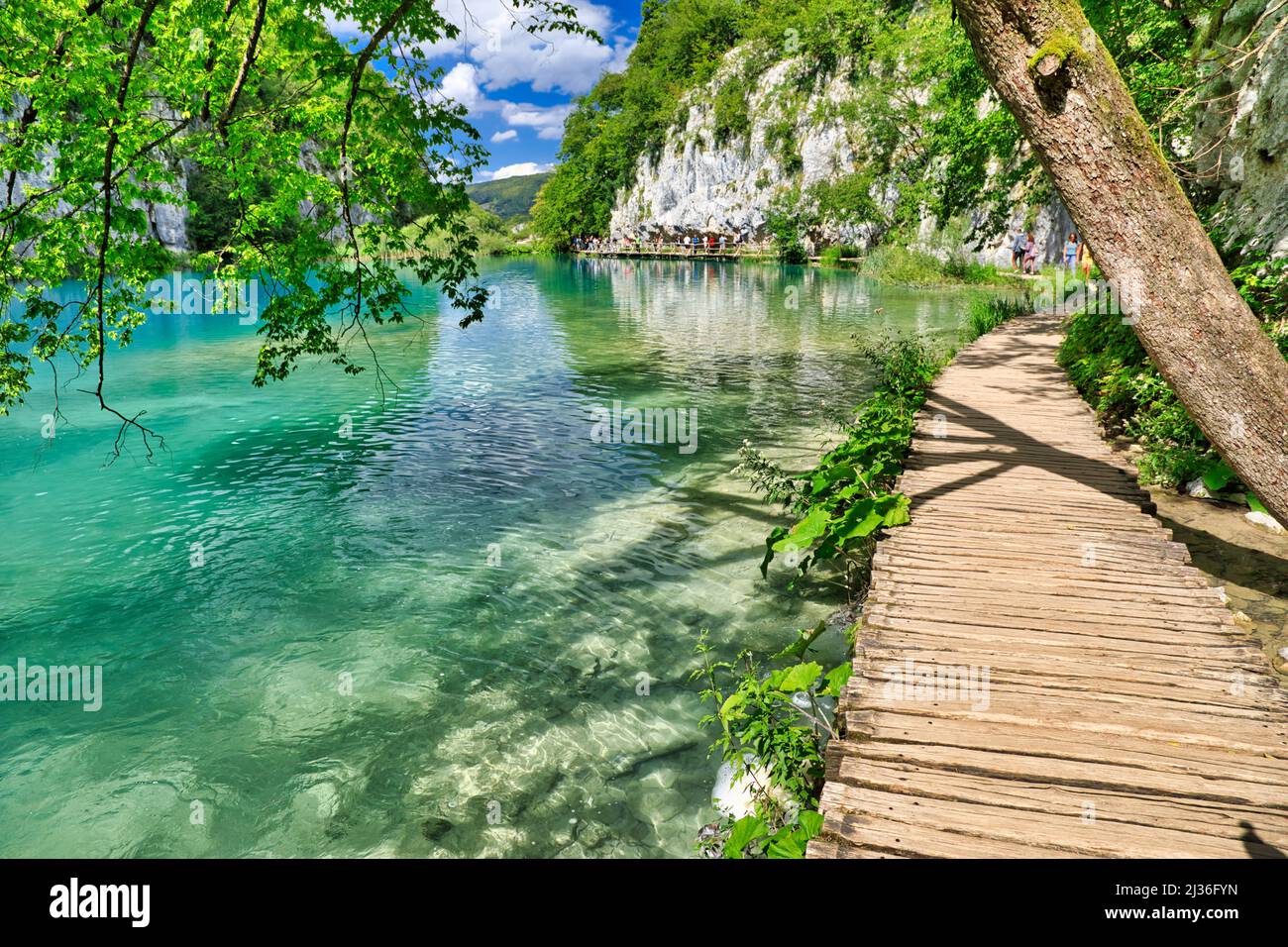 Passeggiando lungo il ponte in legno sul lago Milanovac del Parco Nazionale dei Laghi di Plitvice in Croazia, nella regione di Lika. Patrimonio mondiale dell'UNESCO della Croazia Foto Stock