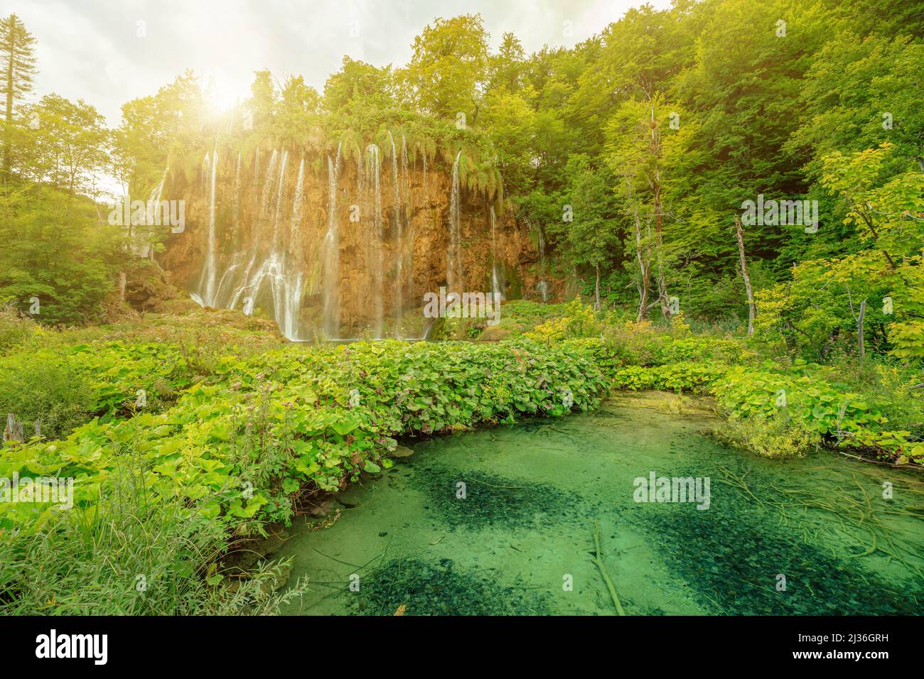 Il sole sulla cascata di Veliki Prstavac si riflette nel lago Potok Plitvice del Parco Nazionale di Plitvice in Croazia. Patrimonio mondiale dell'UNESCO della Croazia Foto Stock