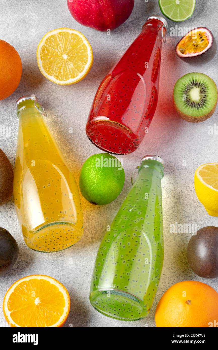 Frutta varia e succo di frutta appena spremuto in bottiglia su sfondo grigio Foto Stock