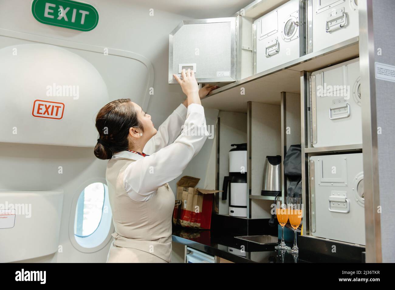 Air hostess prepara il cibo utilizzando un armadietto di sicurezza dell'equipaggio nella cabina di volo. Foto Stock