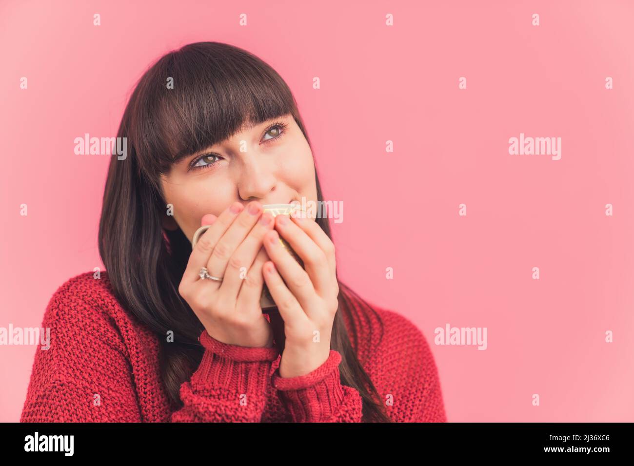 Giovane bella donna europea bere tè, caffè e guardando in studio shot isolato rosa sfondo copia spazio medio primo piano . Foto di alta qualità Foto Stock