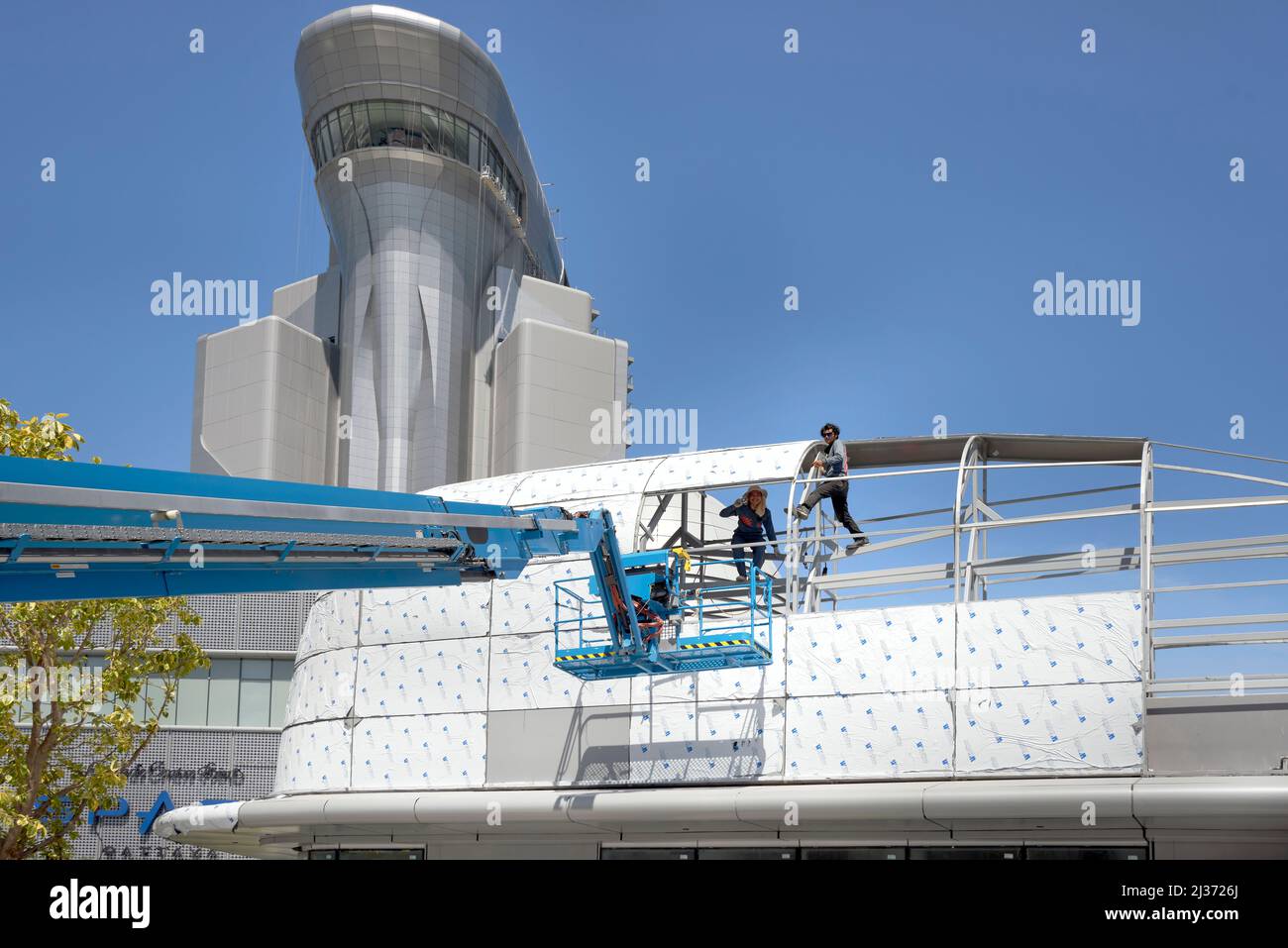 Macchina con braccio telescopico Genie Lift con culla e cesto di sicurezza per uomini che lavorano in alto sulla sezione del tetto di una nuova costruzione Foto Stock