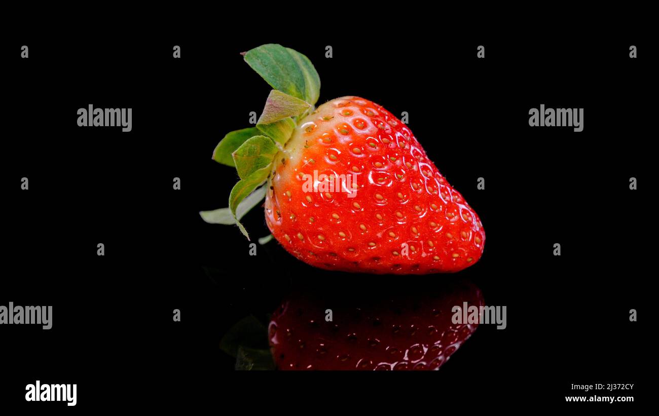 Fragola su sfondo nero vista ravvicinata. Fragola fresca, biologica e vibrante. Spuntino estivo vegano crudo. Foto Stock