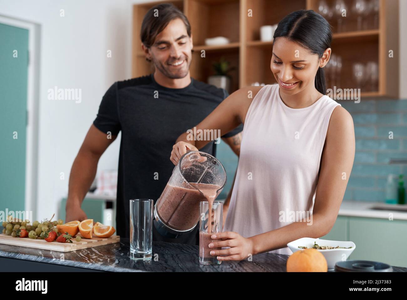 Posso versare un bicchiere. Scatto corto di una giovane coppia affettuosa che fa i frullati nella loro cucina a casa. Foto Stock