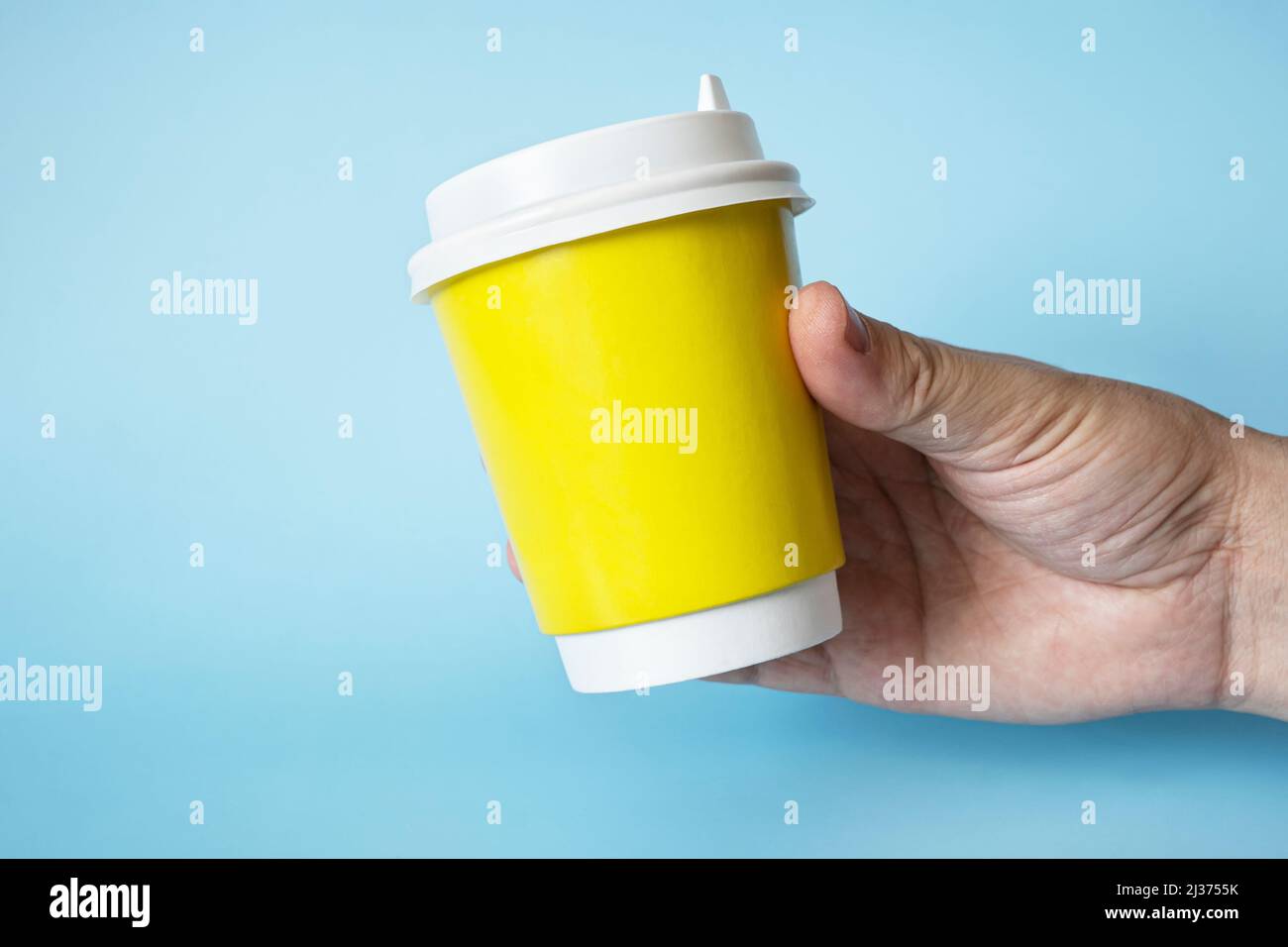 Tazza di carta di caffè in mano dell'uomo. Tazza di carta per bevande calde. Idea per layout isolato su sfondo a colori, colore della carne, spazio libero per il testo Foto Stock