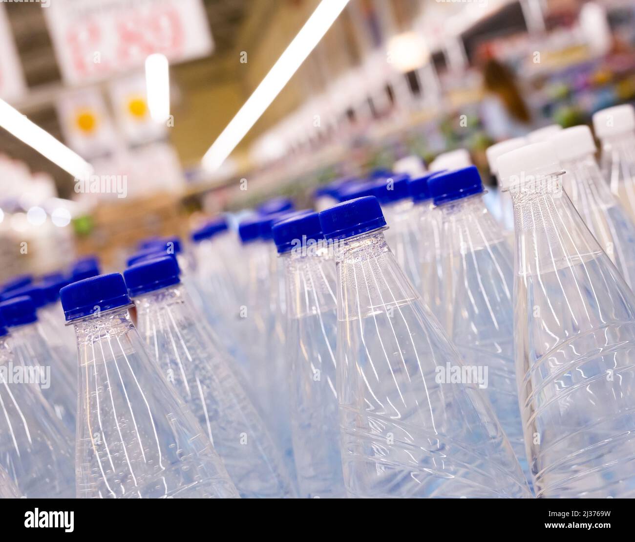 bottiglie d'acqua con tappi blu nel supermercato Foto Stock