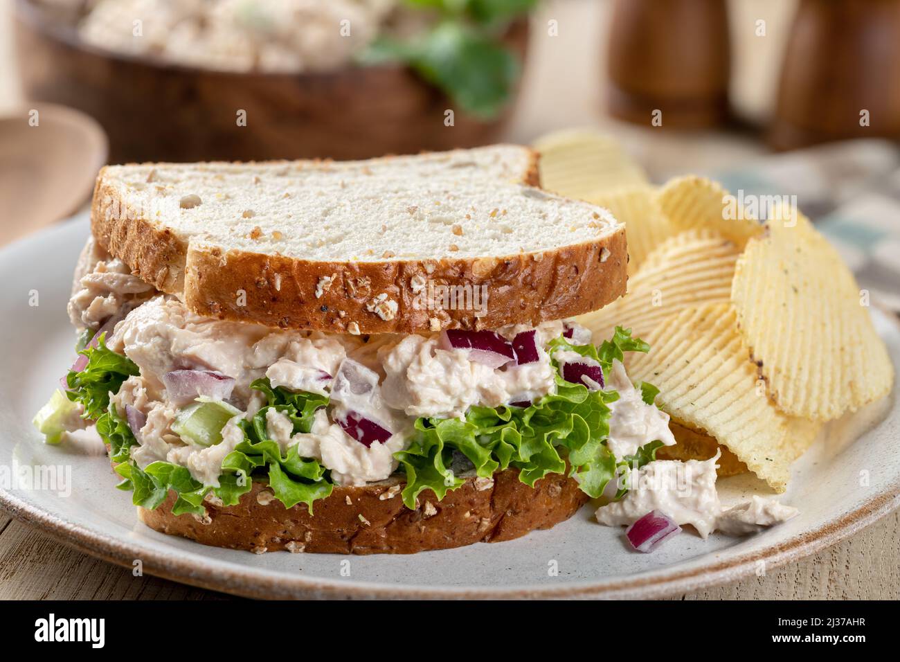Primo piano di un'insalata di tonno e sandwich di lattuga su pane intero con patatine fritte su un piatto Foto Stock