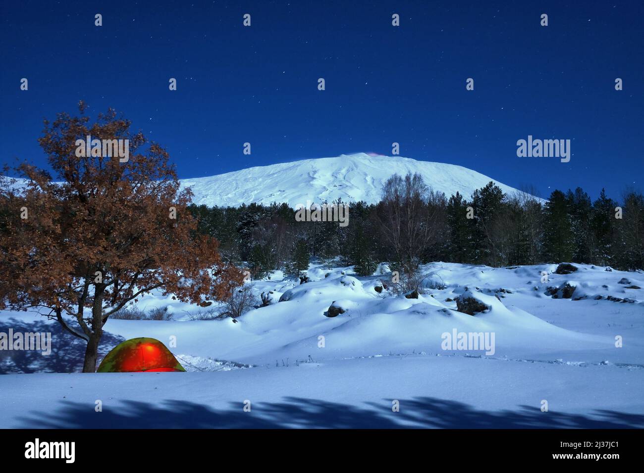 Tenda illuminata e paesaggio invernale del Parco dell'Etna al chiaro di luna, Sicilia Foto Stock