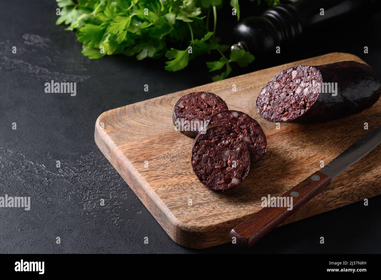 Morcilla di salsiccia di sangue servita su vassoio di legno su sfondo nero con spazio copia. Primo piano. Cucina coreana. Foto Stock